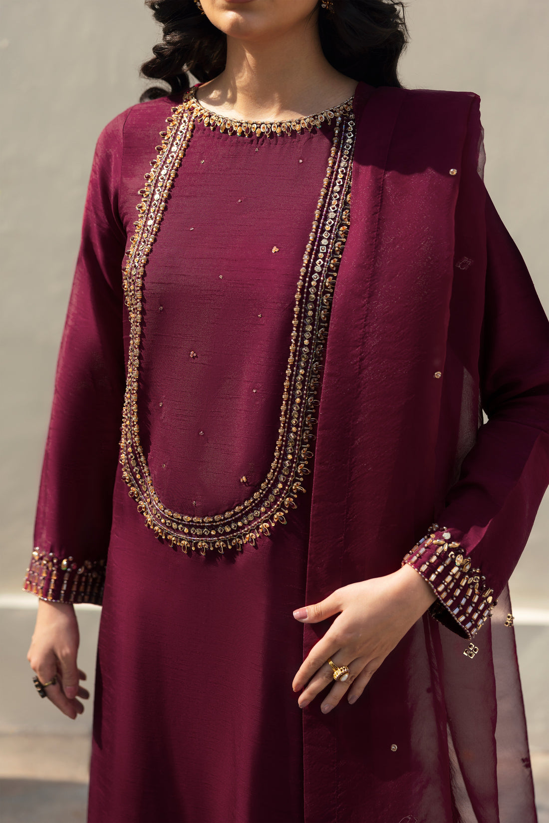 NAQSHI Parize burgundy raw‑silk straight shirt with boat neckline richly adorned in hand‑adda embellishments—kora, dabka, naqshi, sitara, cut dana, crystals & stonework; paired with skin‑tone sequin embroidery culottes.
