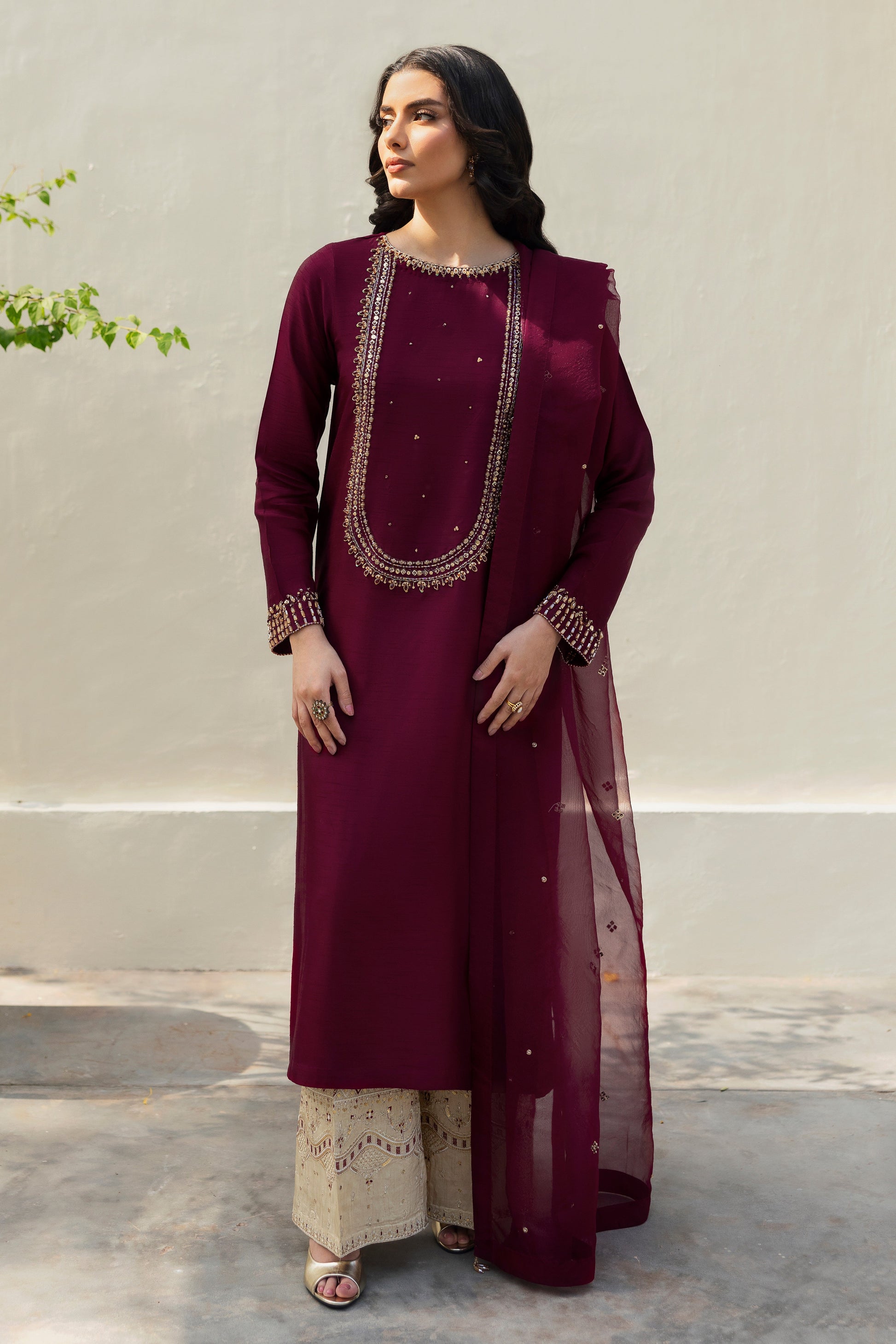 Stylized ensemble Model wearing full NAQSHI Parize set: burgundy hand‑adda shirt, skin culottes with sequin detailing and crystal‑tassel organza dupatta for a refined festive look.