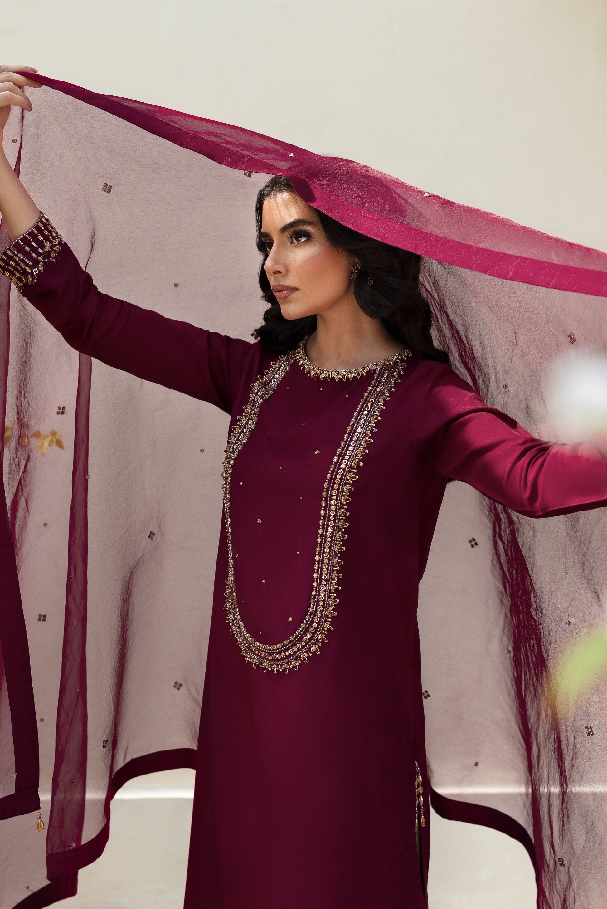 Close‑up of NAQSHI Parize shirt neckline and upper sleeve featuring ornate hand‑adda work combining kora, dabka, stone, cut dana and crystal embroidery on burgundy raw‑silk.