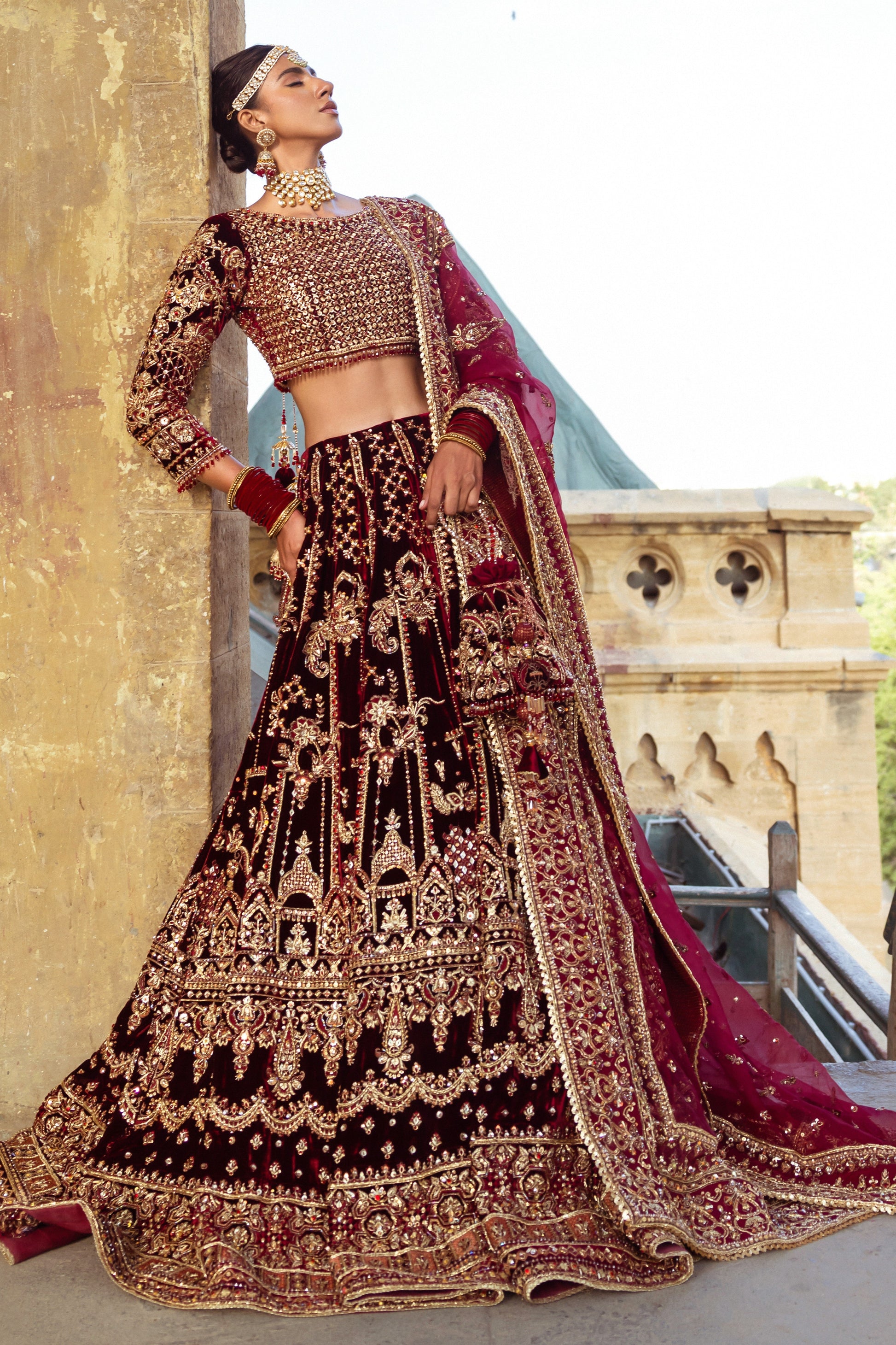 Side pose of Parivarsh maroon bridal dress showing wide lehenga flare and long dupatta trail, traditional ready made wedding attire.