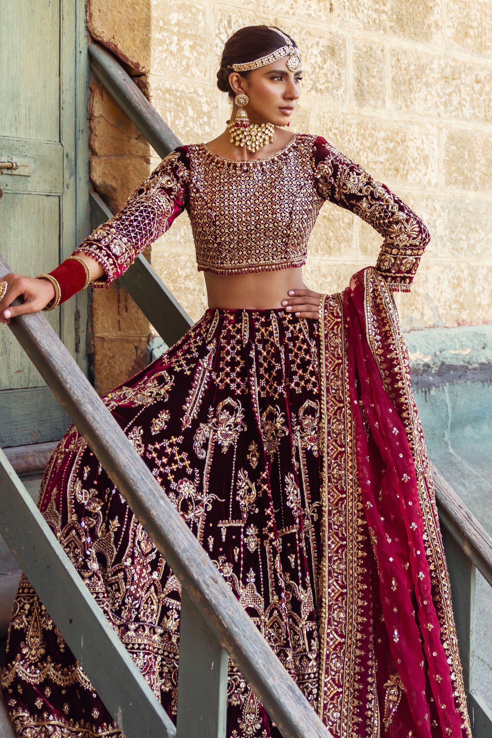 Staircase styling look of Parivarsh velvet lehenga choli highlighting heavy embroidery and structured silhouette, formal bridal barat outfit.