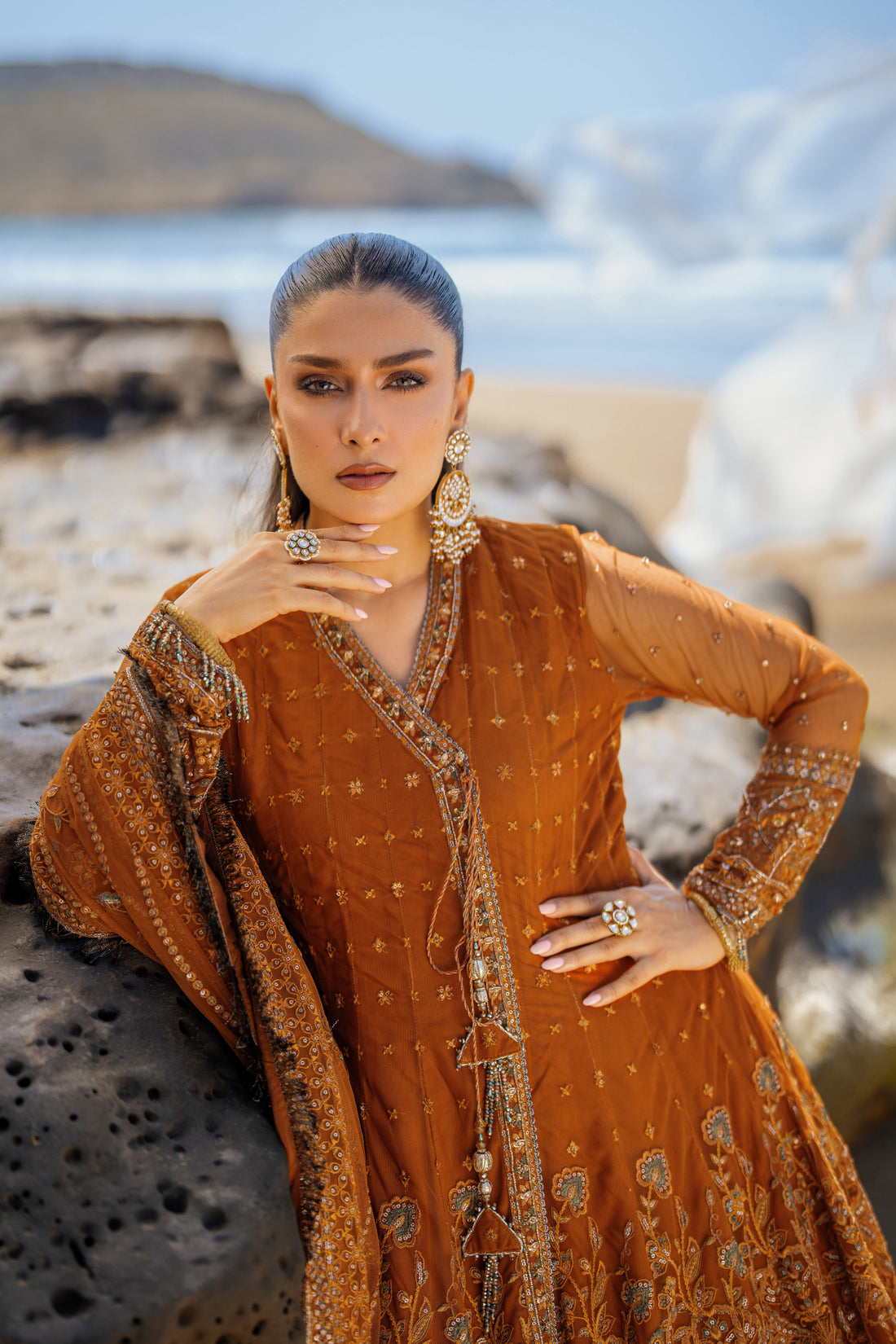 NAQSHI Tianaa rust net angrakha frock front view showcasing heavily embroidered floral and geometric motifs, sequin accents, dome-shaped embroidered border, floor-length cutline.