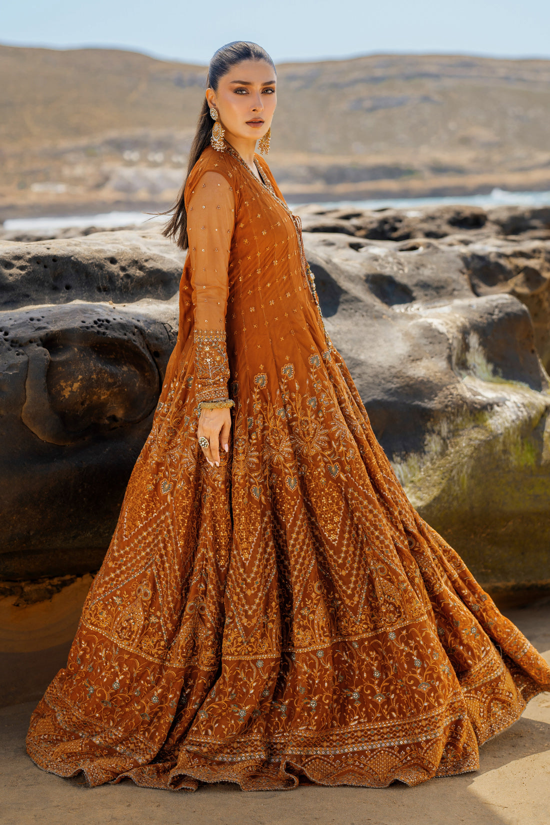 NAQSHI Tianaa rust net angrakha frock front view showcasing heavily embroidered floral and geometric motifs, sequin accents, dome-shaped embroidered border, floor-length cutline.