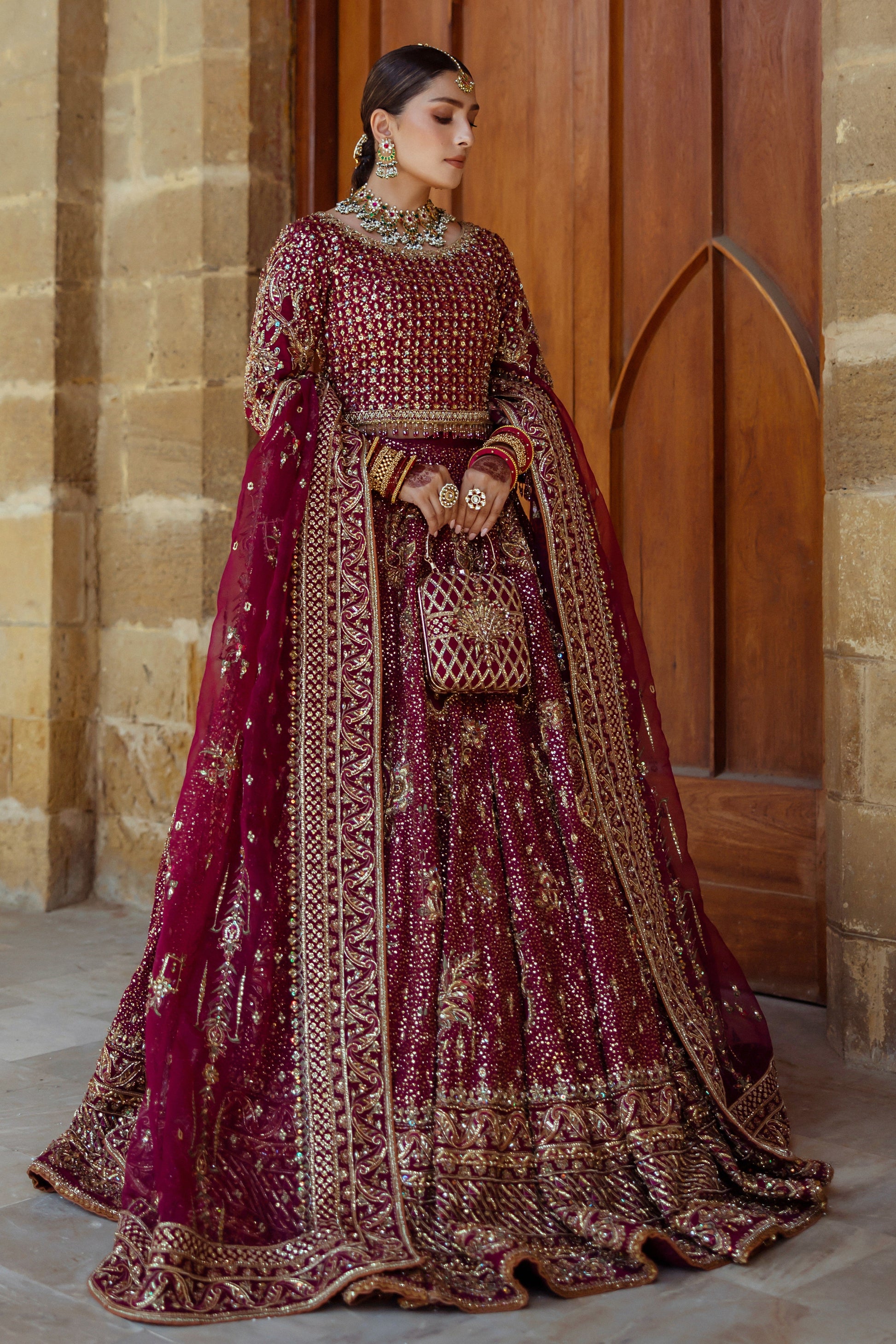 Side pose of Kandhari plum bridal lehenga showing full flare and balanced fall of raw silk fabric, formal ready to wear wedding dress. 