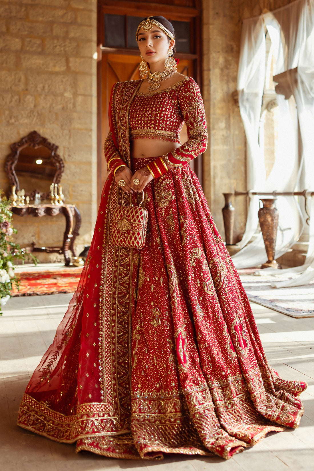 Shahana crimson red bridal lehenga choli by NAQSHI, full front view with heavily embellished raw silk choli, flared lehenga, organza dupatta and matching clutch, ready to wear 4-piece barat wedding outfit.