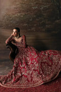 Afrozeh The Brides Edit 23 Adelaide bridal gown in brick red net with gold embellishments, model seated elegantly on a vintage chair.