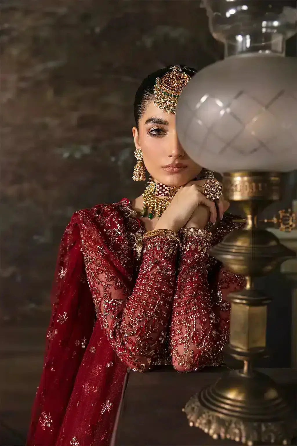 Detailed view of Afrozeh The Brides Edit 23 Emmaine bridal dress highlighting ornate jewelry and maroon net fabric with gold embroidery.