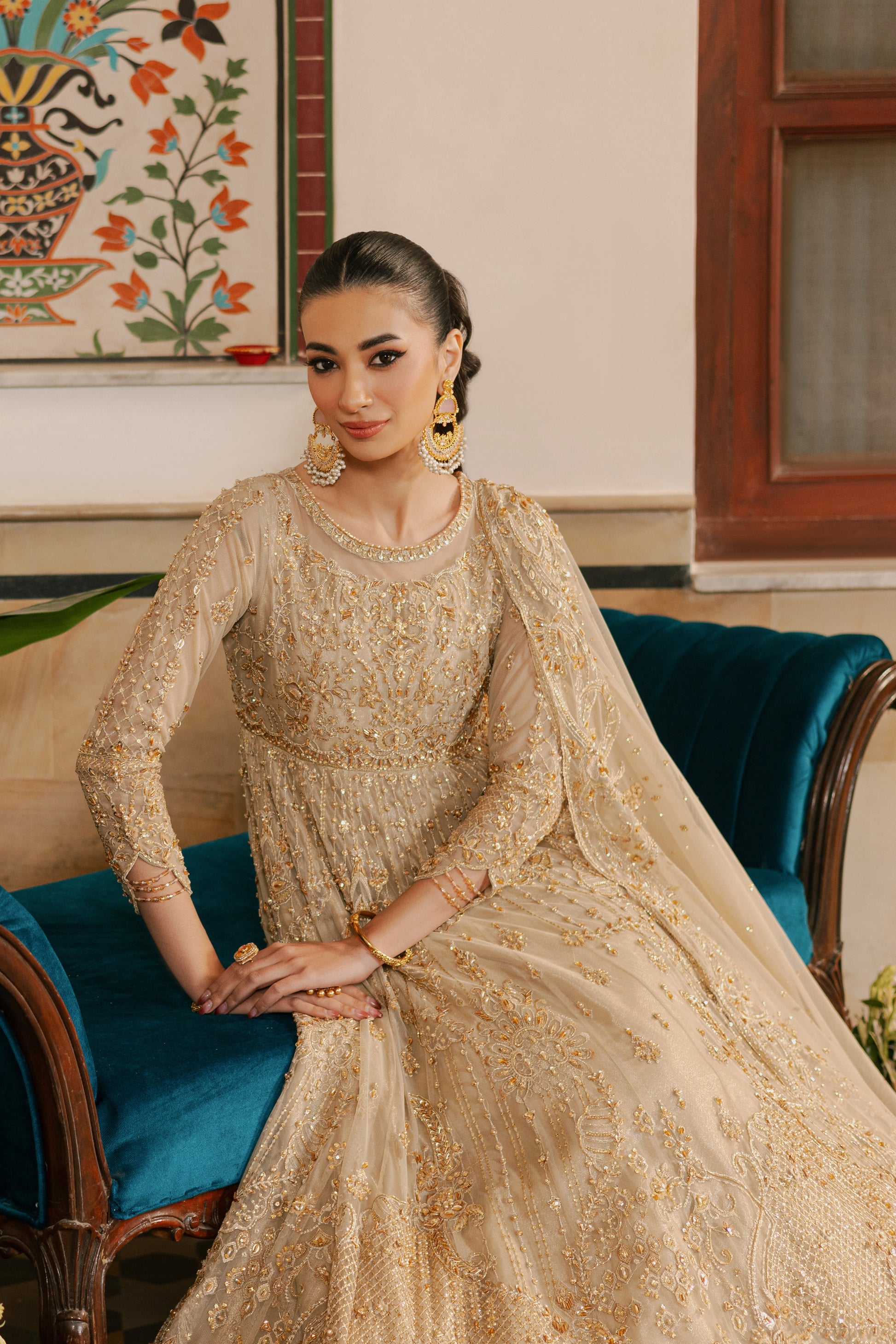 Model wearing complete NAQSHI Maneha 4PC set: heavily embellished champagne‑gold maxi frock, straight silk pants, embellished net dupatta & clutch