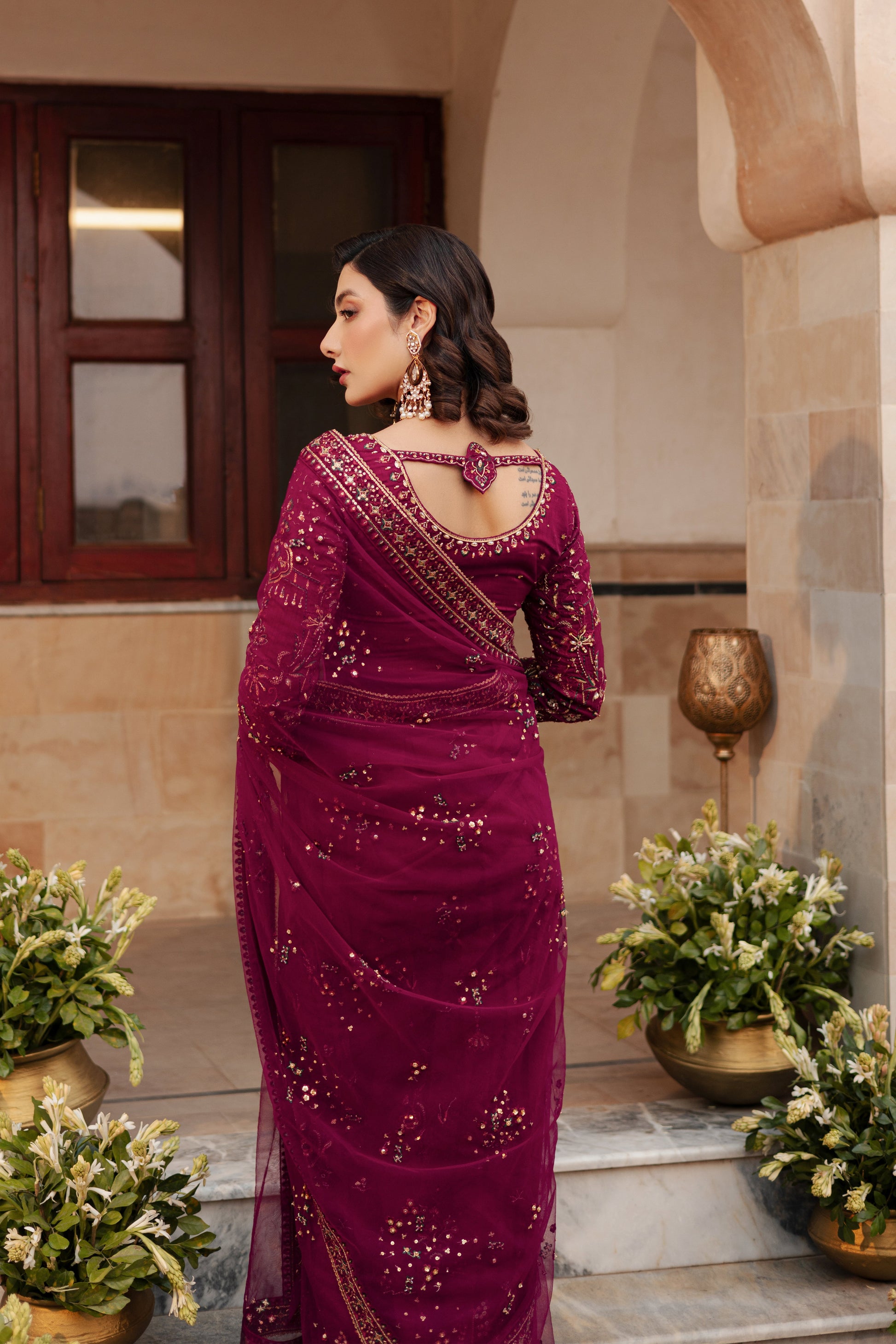 NAQSHI Meeru saree side angle highlighting the rich burgundy color, fine net fabric, and heavy embellishment work across the saree