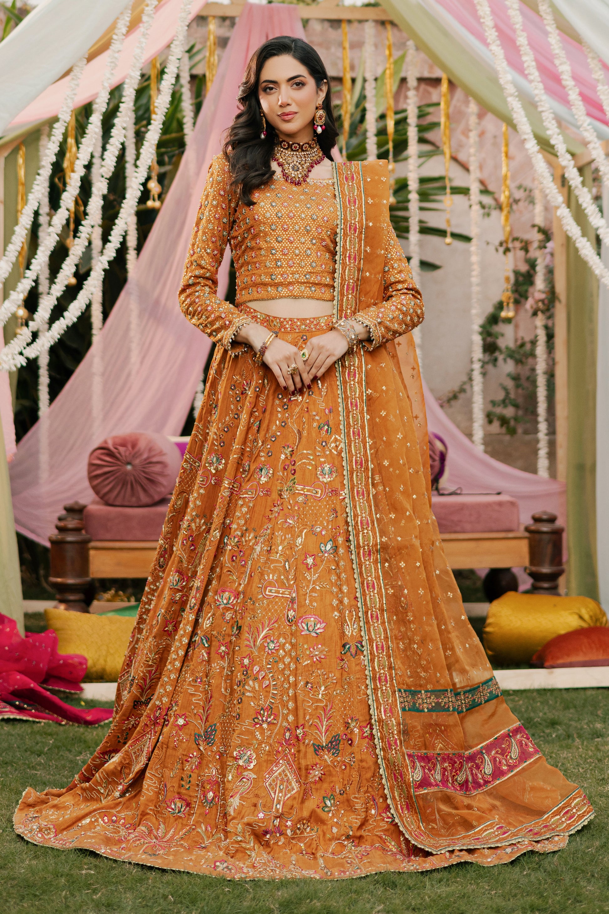 Model styled in full NAQSHI Romanvi 3PC set: tangerine raw‑silk lehenga choli, boat-neck choli, handmade tassels and embroidered organza dupatta